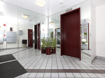 A hallway with a red door and a plant in a red pot.